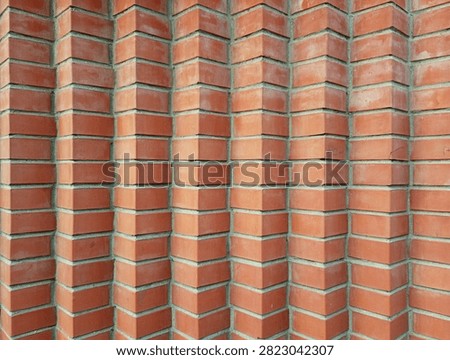 Modern red brick wall texture with a unique geometric zig-zag 3D relief pattern, creative architectural facade design forming vertical rows and optical illusion background.