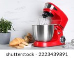 Modern red stand mixer, croissant and cookies on light gray marble table