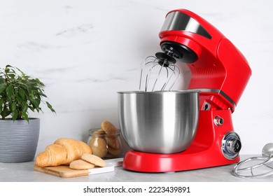 Modern red stand mixer, croissant and cookies on light gray marble table