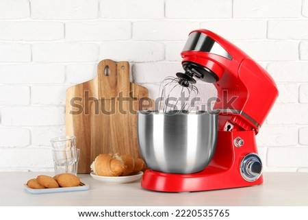 Modern red stand mixer, croissant and cookies on white wooden table
