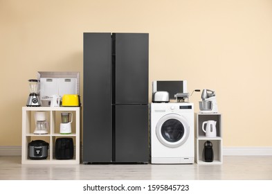 Modern refrigerator and other household appliances near beige wall indoors - Shutterstock ID 1595845723