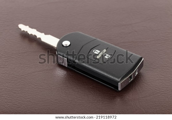 Modern remote\
car key on brown leather\
background