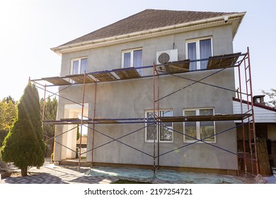Modern repair and reconstruction of the house. Insulation of the house with polystyrene foam, plastering, applying plaster and painting facade walls using scaffolding when repairing the house.