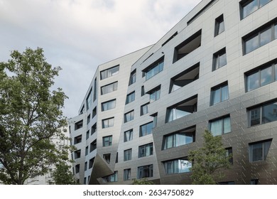 A modern residential building featuring an angular, irregular facade clad in metallic panels. 
