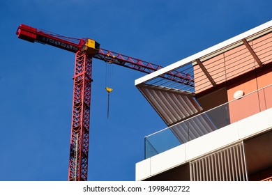 modern residential building roof parapet detail with sun shade grills and shading. brick exterior detail. tall red steel construction tower crane in a distance. blue sky. building industry concept. - Shutterstock ID 1998402722