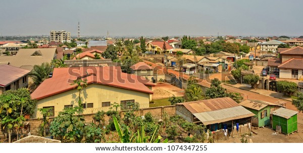 Modern\
residential buildings in Africa. Suburb lifestyle in developing\
countries. Beautiful urban landscape. Top view. Wonderful houses\
with red tile roofs, yards, fences, roads,\
cars