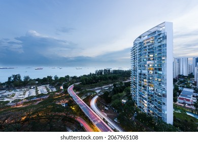 Modern residential condominium building complex overlooking the Singapore sea strait and a highway overpass, at sunset, in Singapore
