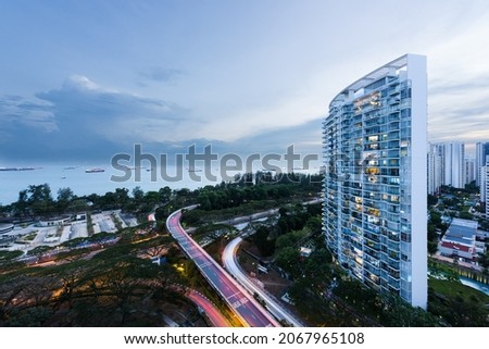 Modern residential condominium building complex overlooking the Singapore sea strait and a highway overpass, at sunset, in Singapore