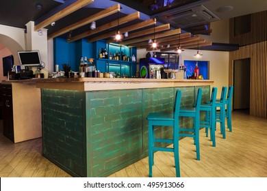 Modern Restaurant Or Cafe Interior. Public Place Interior Design, Bright Blue Wooden Chairs, Large Bar Counter Desk. Morning Light, Nobody Indoors.