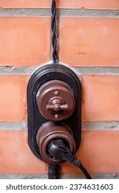 Modern retro switch and socket with twisted wire on a brick wall background.