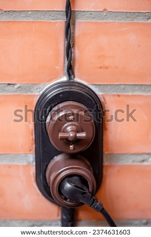 Modern retro switch and socket with twisted wire on a brick wall background.
