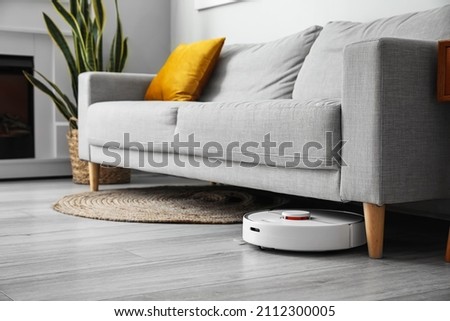 Modern robot vacuum cleaner near sofa in room Сток-фото © 