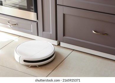 Modern robot vacuum cleaner on floor in kitchen