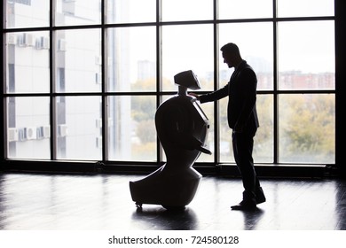 Modern Robotic Technologies. A man communicates with a robot, presses a plastic mechanical arm to the robot, handshake.