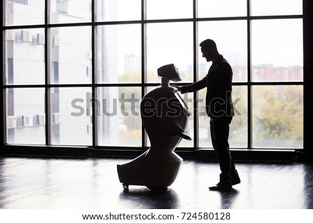 Modern Robotic Technologies. A man communicates with a robot, presses a plastic mechanical arm to the robot, handshake.