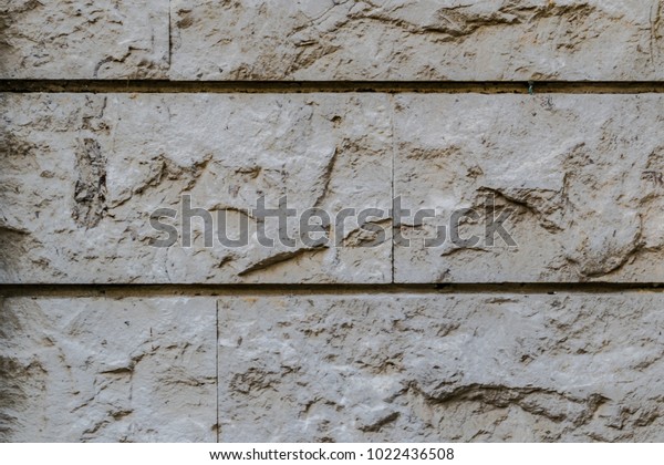 Modern rock wall texture made with gray
rock tiles, two orizzontal lines divide the image

