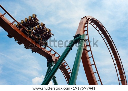 Modern Rollercoaster in Motion with People Riding on a Clear Summer Day