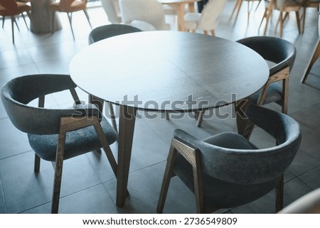 Modern round dining table with comfortable upholstered chairs creating a contemporary cafe interior design
