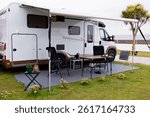 Modern rv camper setup with retractable awning at coastal campsite