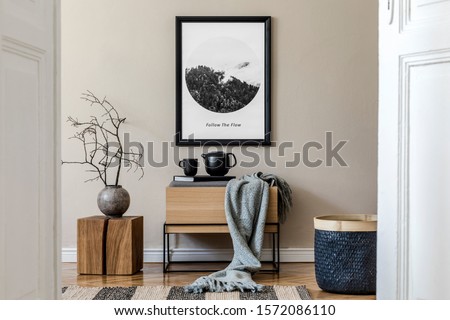 Modern scandinavian living room interior with black mock up poster frame, design commode,  leaf in vase, black rattan basket, books and elegant accessories. Template. Stylish home decor. 