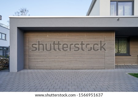 A modern Scandinavian-style garage with a wood-paneled garage door. Private garage with automatic door in a European city in Germany