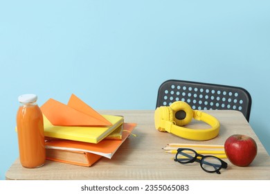 Modern school desk with lunch and stationery in room near blue wall - Powered by Shutterstock