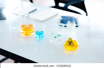 Modern Science Research Lab With Beaker Glass And Colorful Sample Liquid On Table In White Blur Background, Experimental Human Vaccine For Clue Coronavirus Or Covid 19