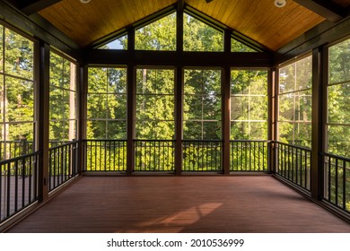Modern screened porch enclosure with plastic windows and composite floor with summer woods in the background.