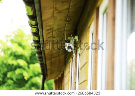 Modern Security Camera Mounted on Wooden House Exterior for Home Surveillance