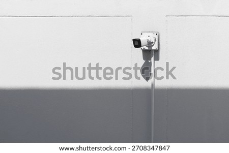 Modern security CCTV camera mounted on clean white wall. Safety system, home security, surveillance technology, privacy protection, outdoor monitoring and minimal architectural background.