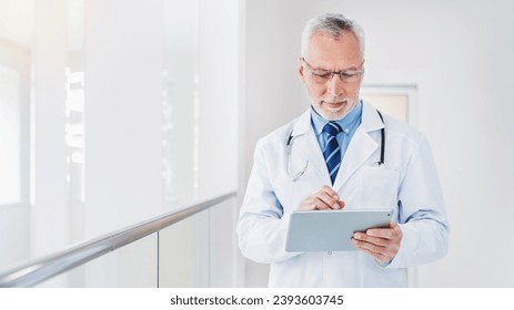 Modern senior doctor using tablet pc in clinic for online medicine, telemedicine. Remote prescription of drugs medicals pills. Family doctor consulting remotely - Powered by Shutterstock