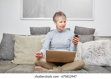 Modern senior woman on her couch using smartphone - Powered by Shutterstock