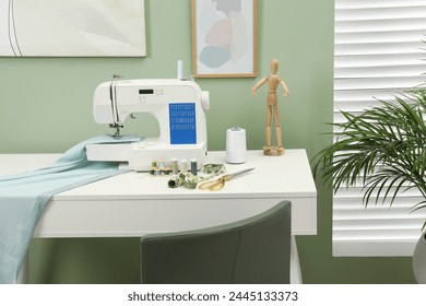 Modern sewing machine with cloth and craft accessories on white table near window in room - Powered by Shutterstock