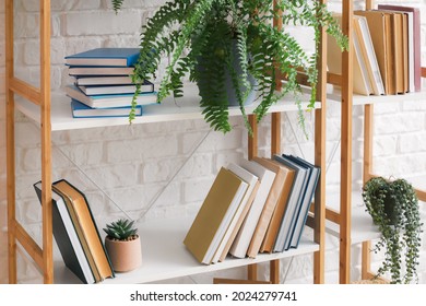 Modern shelf unit with books near brick wall, closeup