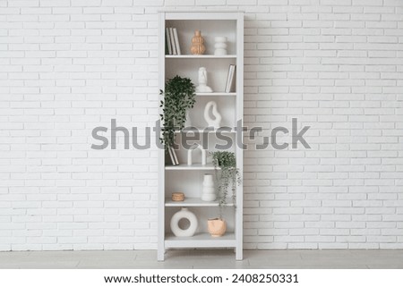 Modern shelf unit near white brick wall