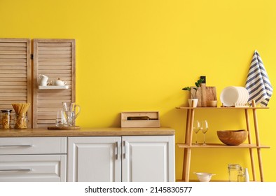 Modern shelving unit with dishware and kitchen counter near yellow wall - Shutterstock ID 2145830577