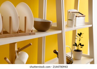 Modern shelving unit with dishware near yellow wall in kitchen, closeup - Shutterstock ID 2144700943