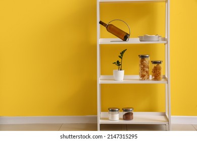 Modern shelving unit with dishware near yellow wall in kitchen - Shutterstock ID 2147315295
