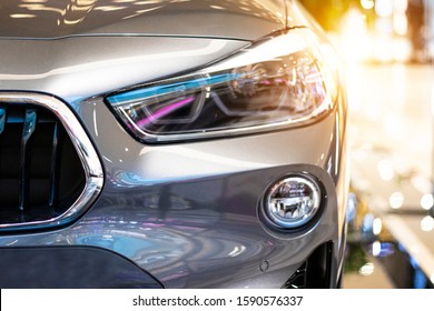 Modern, shiny SUV headlight in a car showroom.