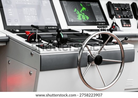 Modern ship helm and navigation control console with steering wheel, throttles, levers and radar screens on a vessel bridge, illustrating marine technology and simulation trainig 