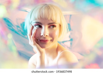Modern short haircuts and make up. Cool smiling blond young girl with perfect brows, shiny glowing facial skin, naked shoulders looks aside dreaming. Female portrait on colourful backdrop.