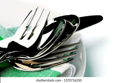 Modern Silverware with Dessert Fork, Dessert Spoon, Table Knife, Spoon and Fork on Green Napkin and Plate closeup on White background