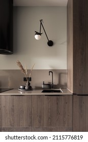 Modern and simple design in kitchen with wooden countertop and cupboards, black sink, tap and kitchen hood