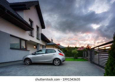 A modern single family house with a car parked outside at sunset