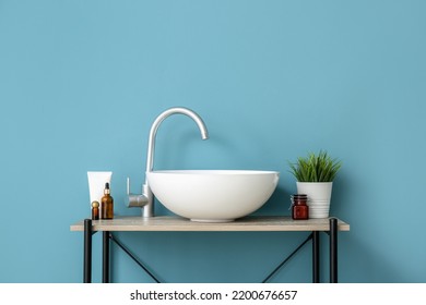 Modern sink, houseplant and bath accessories near blue wall - Shutterstock ID 2200676657