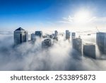 The modern skyline of London, Camary Wharf disctrict, during an autumn day with fog and the tops of the skyscrapers looking out above the clouds