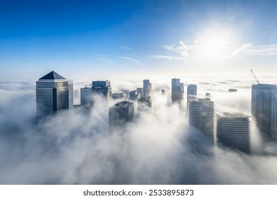 The modern skyline of London, Camary Wharf disctrict, during an autumn day with fog and the tops of the skyscrapers looking out above the clouds - Powered by Shutterstock