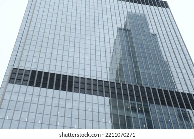 Modern Skyscraper With Glass Windows. From Below Of Contemporary Tall Building With Reflection Of Skyscraper