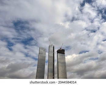 Modern skyscraper under construction with crane. From below of contemporary tall skyscraper with glass walls and with crane against cloudy sky in downtown