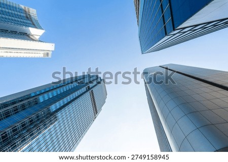 Modern skyscrapers viewed from below with dramatic perspective in a financial district. Glass office towers surrounding the sky represent global business, corporate growth, urban development, and modern city architecture.